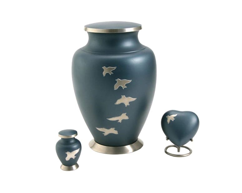 An Aria blue urn with pewter doves in flight, beside its keepsake and heart companions