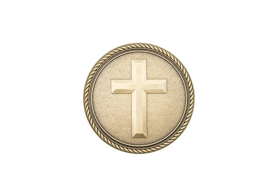 A round brass memorial emblem with a raised cross and rope border