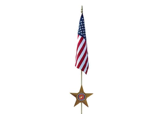 A cemetery flag holder with a bronze service star holding a small American flag