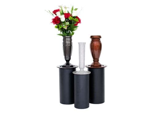 Three flush ground cemetery vases with in-ground sleeves, one arranged with roses