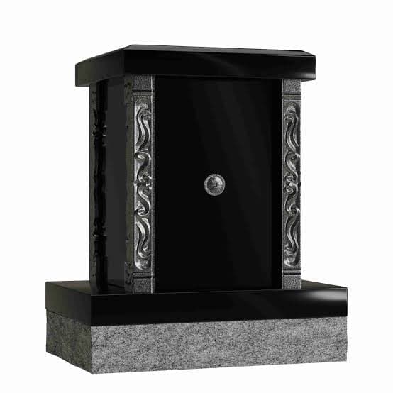 A personal columbarium: a compact pedestal niche with a glass door and an urn resting inside, installed at a cemetery plot